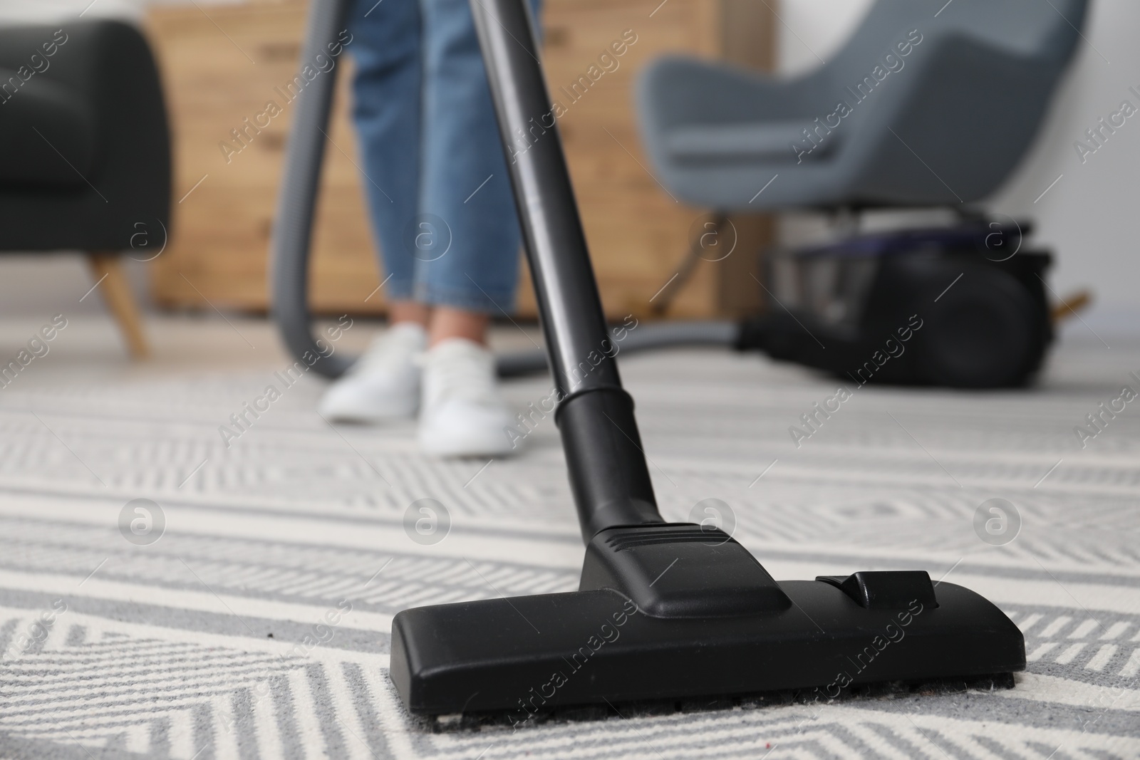 Photo of Woman with vacuum cleaning carpet indoors, closeup