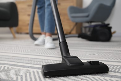 Photo of Woman with vacuum cleaning carpet indoors, closeup