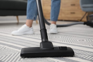 Photo of Woman with vacuum cleaning carpet indoors, closeup