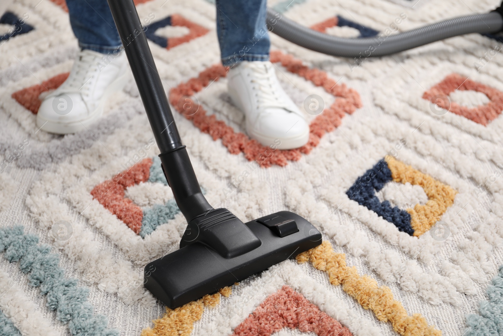 Photo of Man with vacuum cleaning carpet indoors, closeup