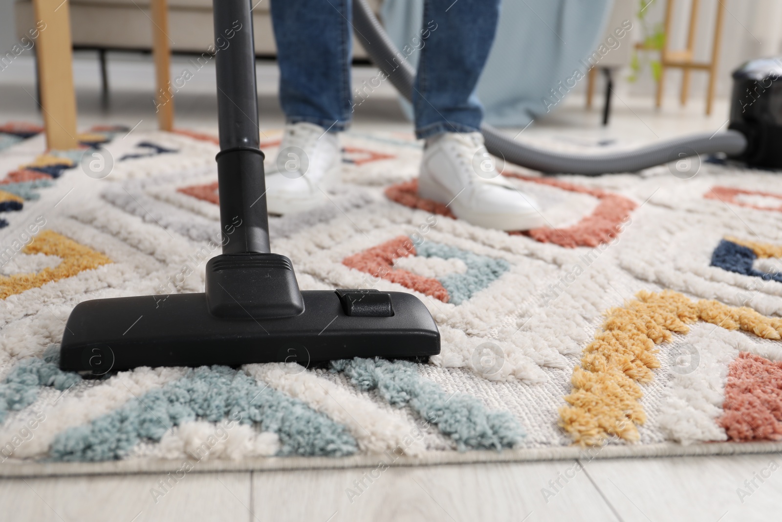 Photo of Man with vacuum cleaning carpet indoors, closeup