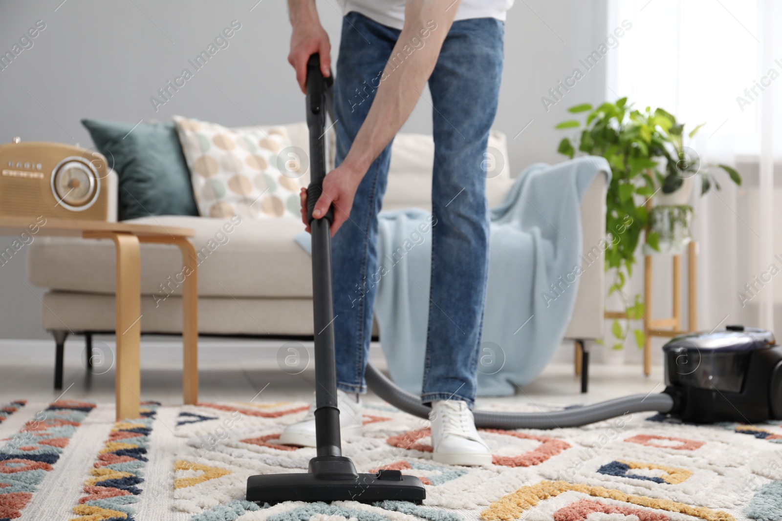 Photo of Man with vacuum cleaning carpet in living room, closeup