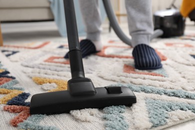 Photo of Man with vacuum cleaning carpet indoors, closeup