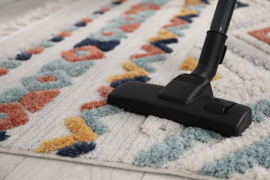 Photo of Cleaning color carpet with vacuum indoors, closeup