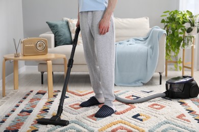 Photo of Man with vacuum cleaning carpet indoors, closeup
