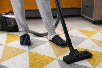 Man with vacuum cleaning carpet indoors, closeup