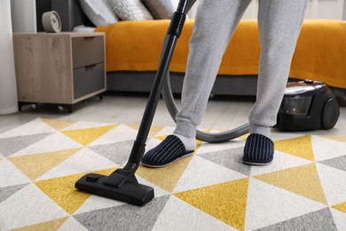 Photo of Man with vacuum cleaning carpet in bedroom, closeup