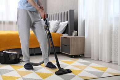 Man with vacuum cleaning carpet in bedroom, closeup