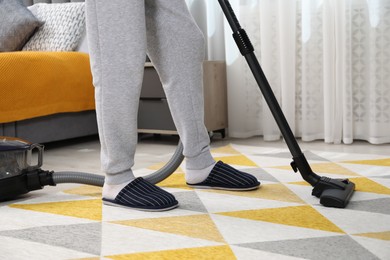 Man with vacuum cleaning carpet in bedroom, closeup