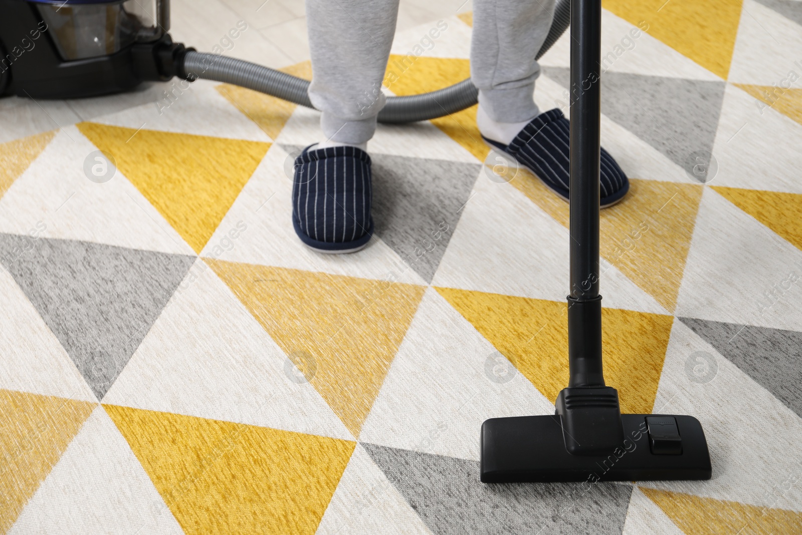 Photo of Man with vacuum cleaning carpet indoors, closeup