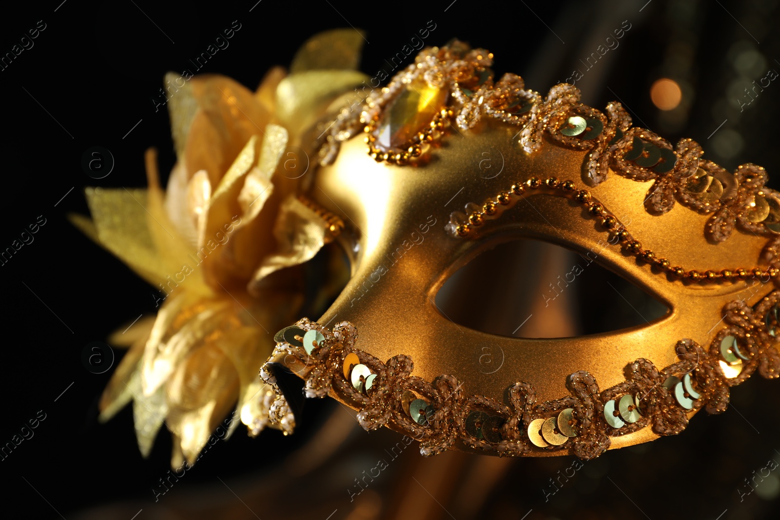 Photo of Beautiful golden carnival mask in darkness, closeup