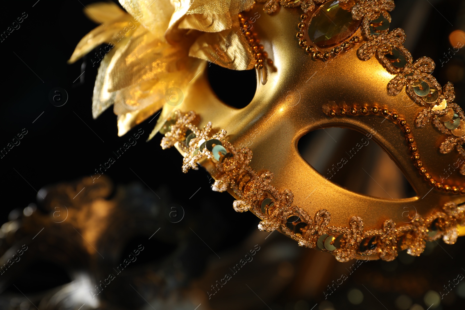 Photo of Beautiful golden carnival mask in darkness, closeup