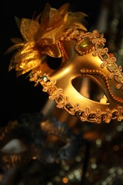 Photo of Beautiful golden carnival mask in darkness, closeup