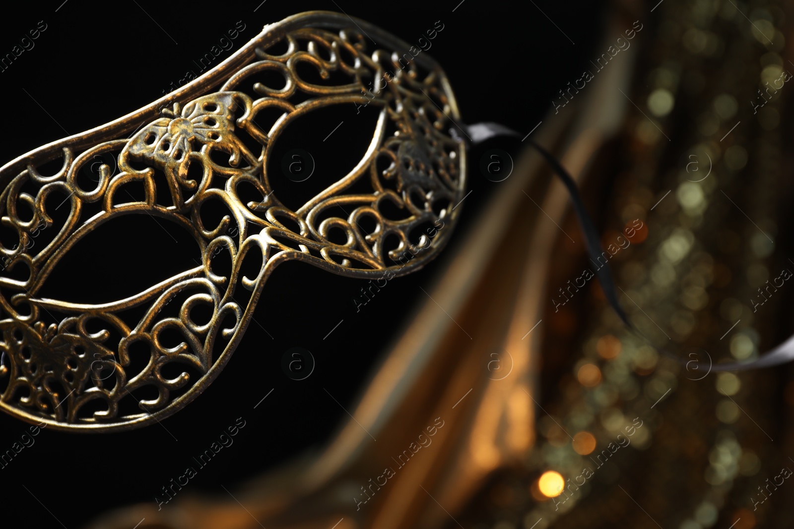 Photo of Beautiful carnival mask in darkness, closeup. Space for text