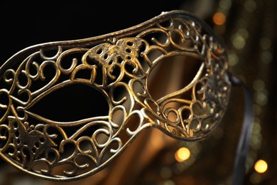 Photo of Beautiful golden carnival mask in darkness, closeup