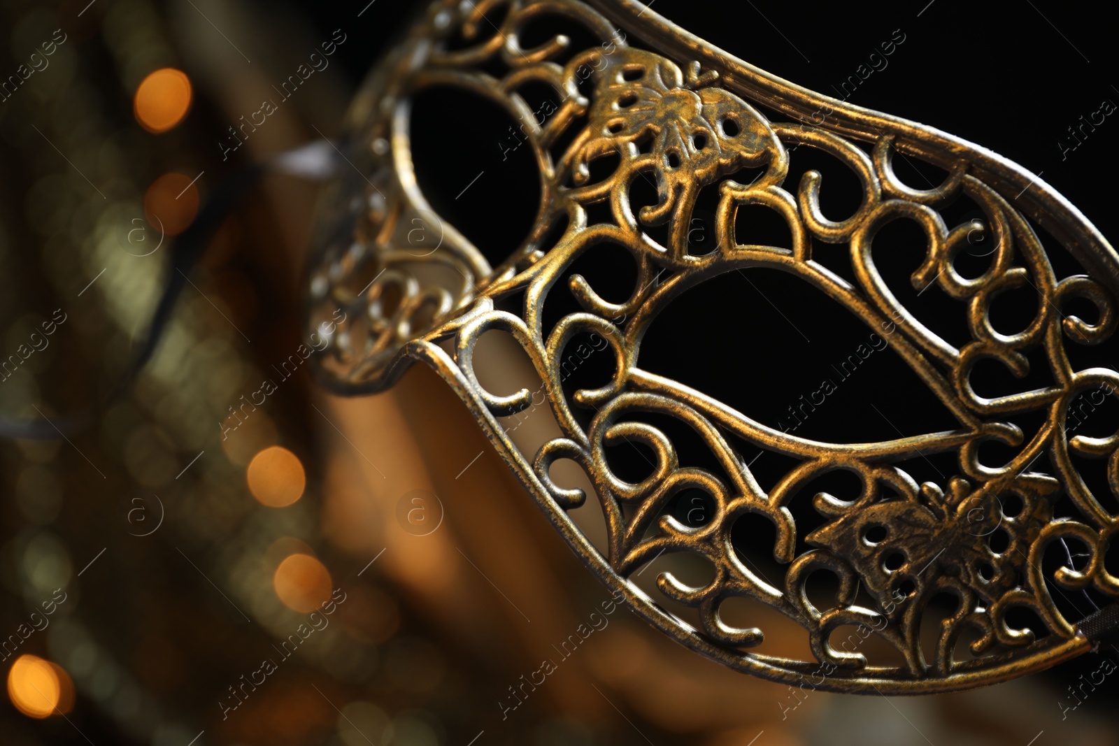 Photo of Beautiful golden carnival mask in darkness, closeup