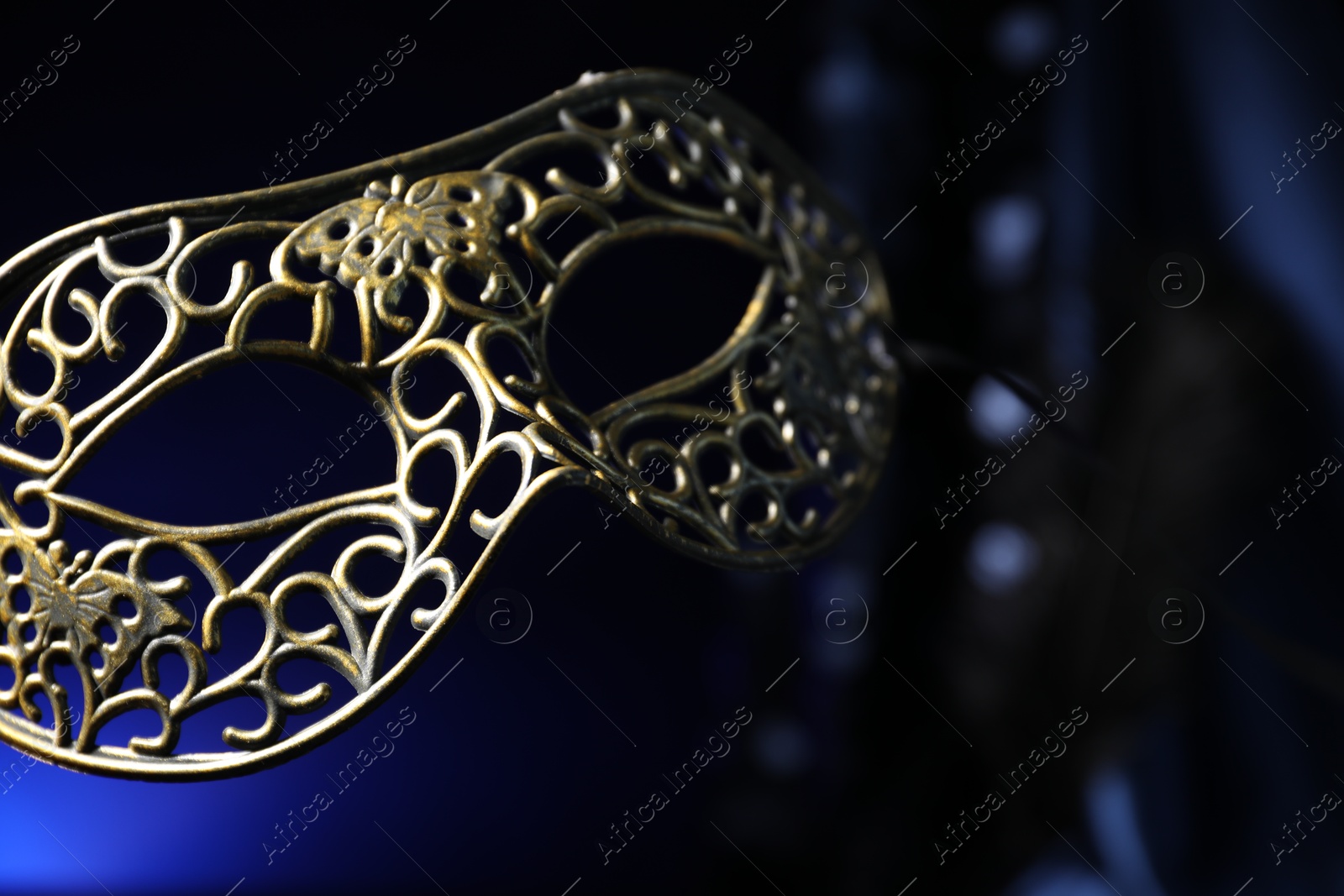 Photo of Beautiful carnival mask in darkness, closeup view