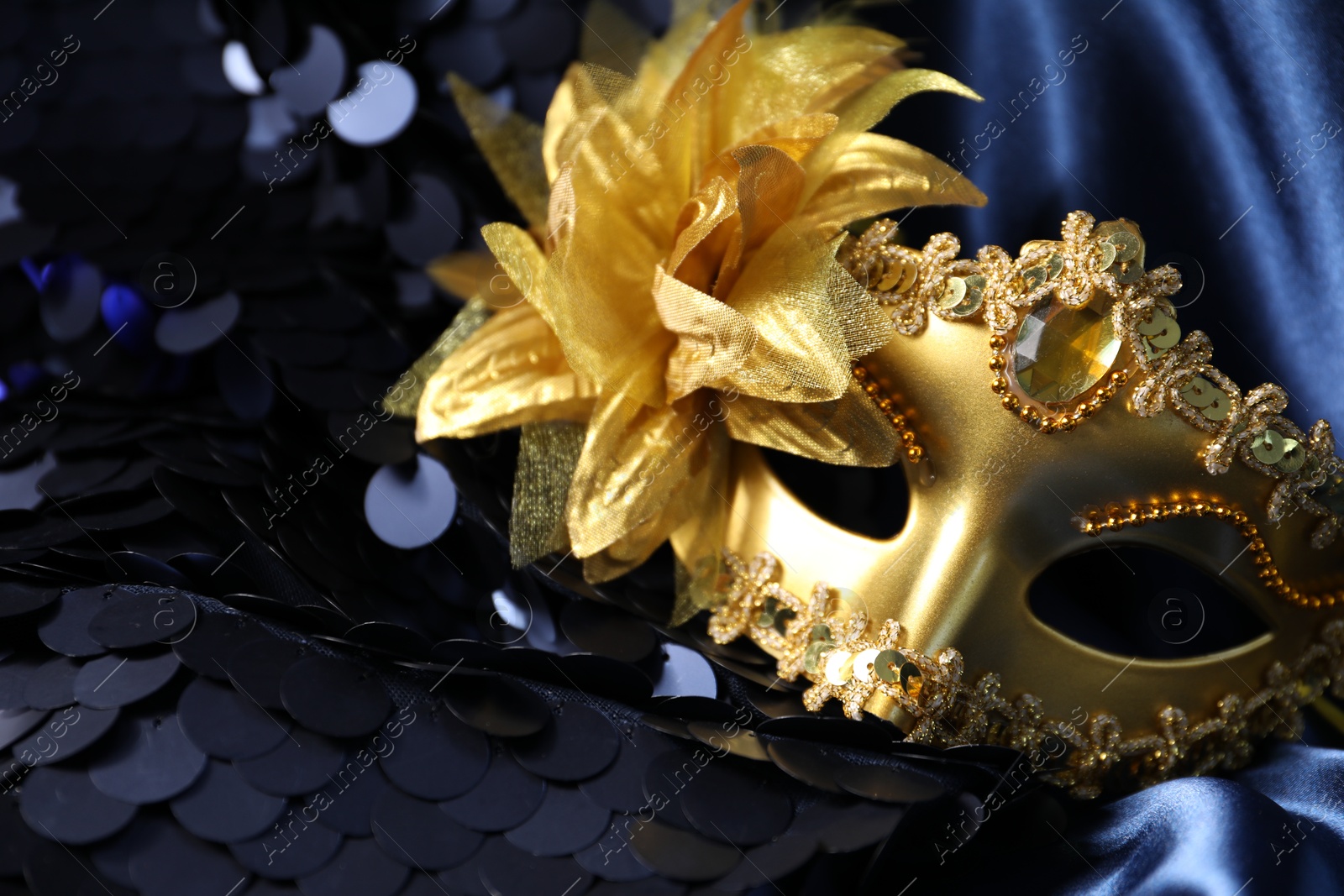 Photo of Beautiful golden carnival mask on dark blue fabric