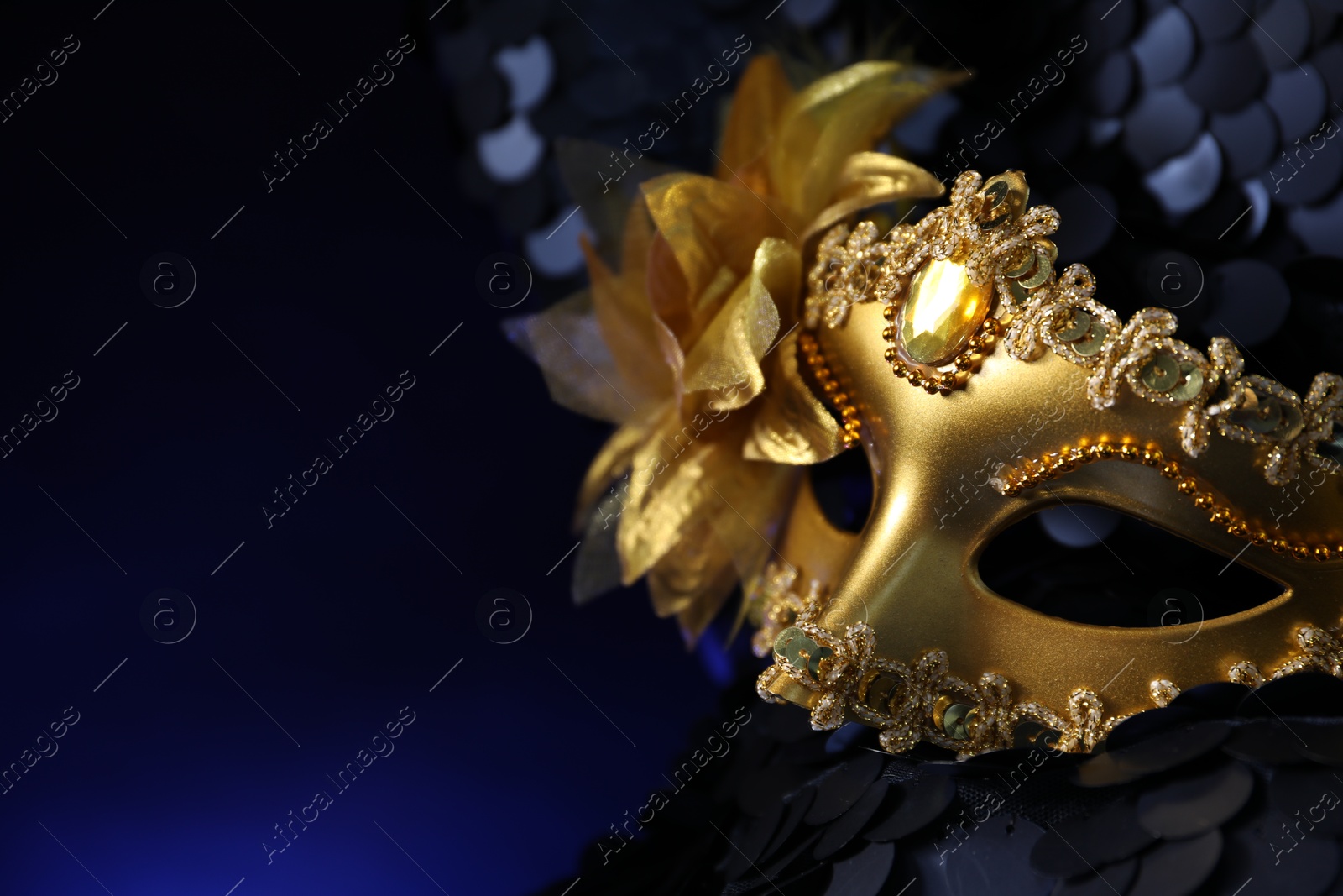 Photo of Beautiful golden carnival mask on dark blue background, closeup. Space for text