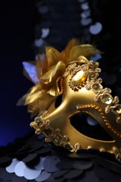 Photo of Beautiful golden carnival mask on dark blue background, closeup