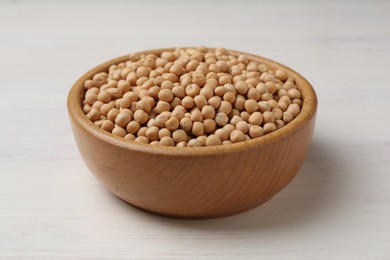 Photo of Dried peas in bowl on light wooden table, closeup