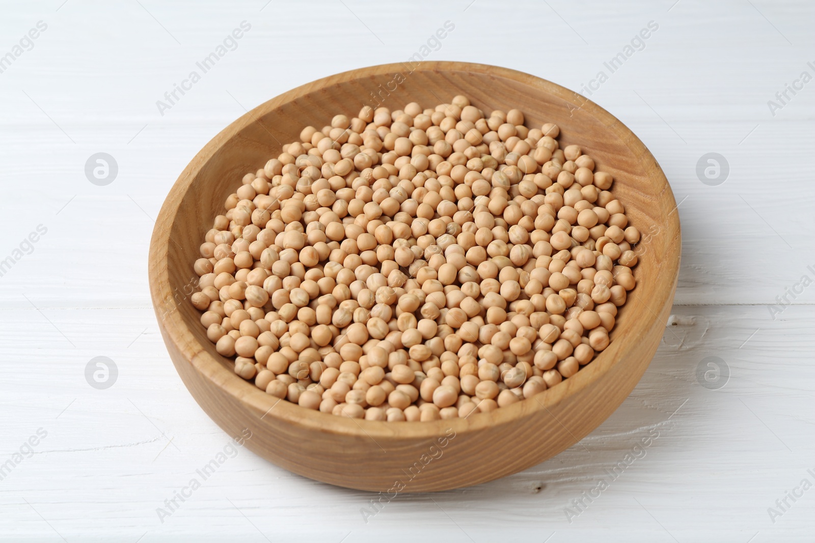 Photo of Dried peas in bowl on white wooden table, closeup