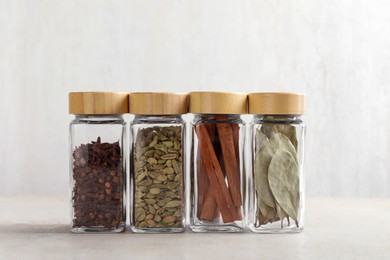 Photo of Different spices in glass jars on light table, closeup