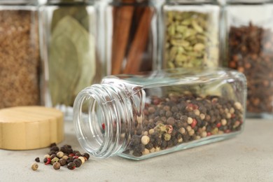 Photo of Different spices in glass jars on light textured table, closeup