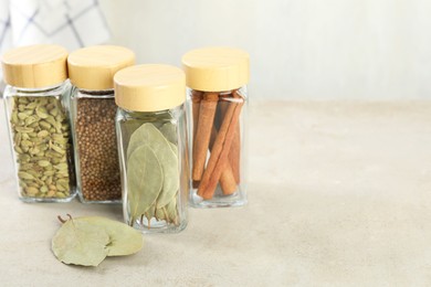 Different spices in glass jars on light textured table. Space for text