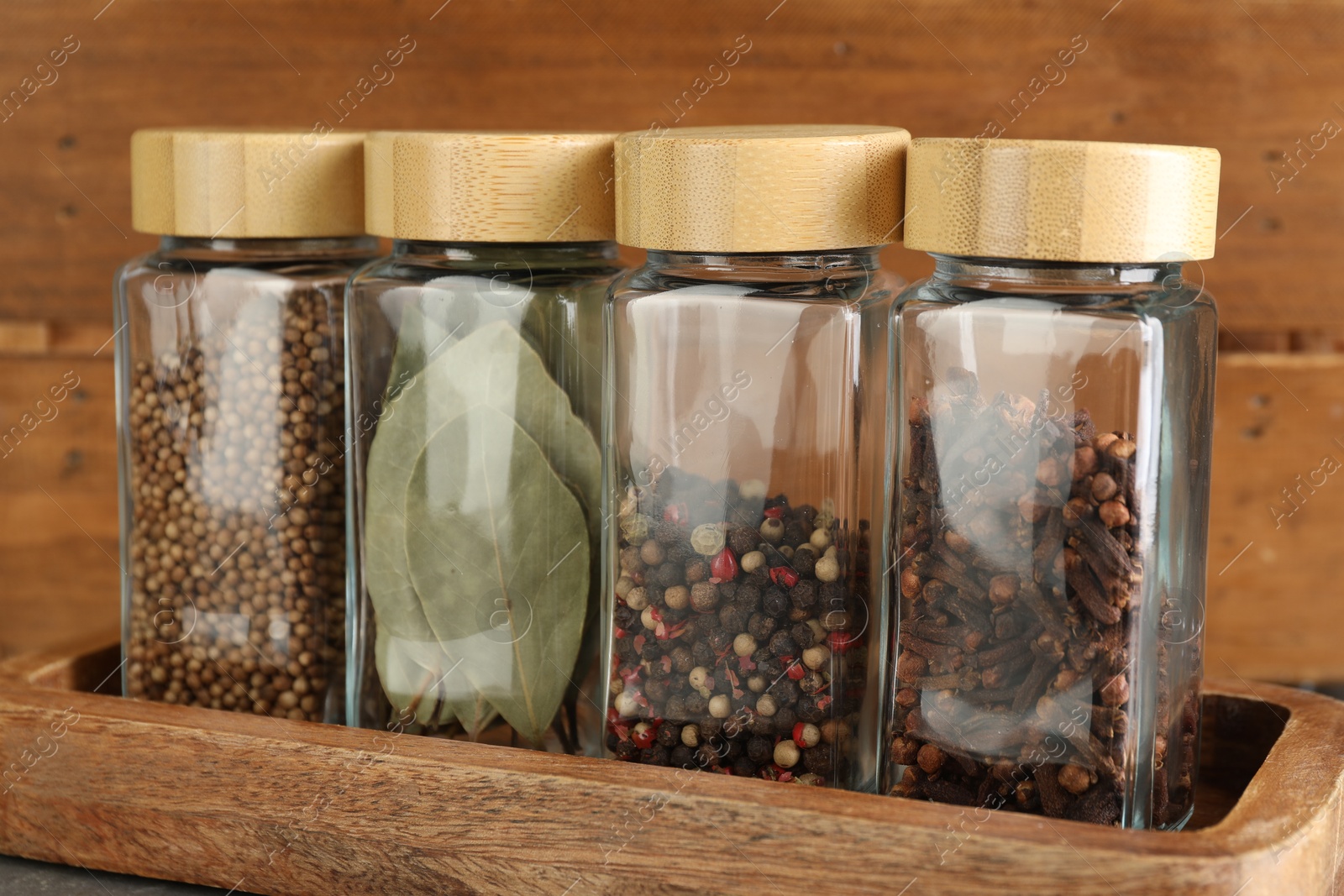 Photo of Different spices in glass jars on table, closeup