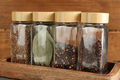 Photo of Different spices in glass jars on table, closeup