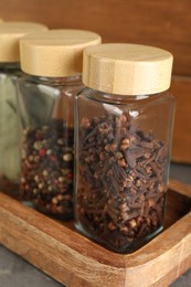 Different spices in glass jars on table, closeup