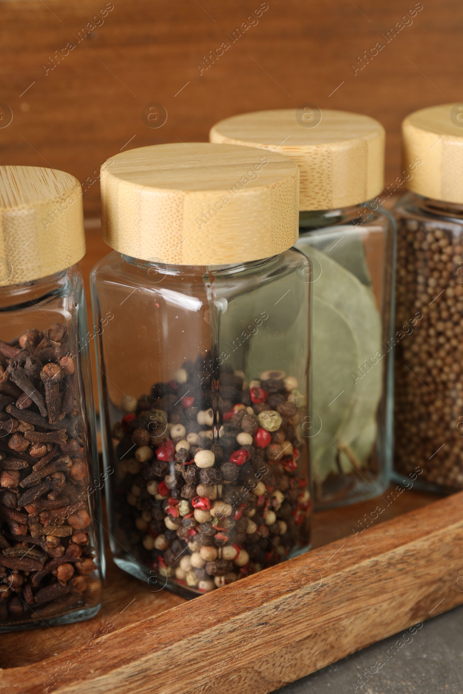 Photo of Different spices in glass jars on table, closeup