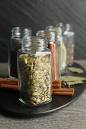 Different spices in glass jars on grey wooden table, closeup