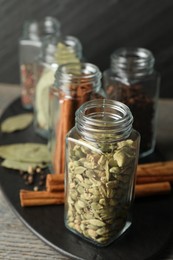 Different spices in glass jars on grey wooden table, closeup