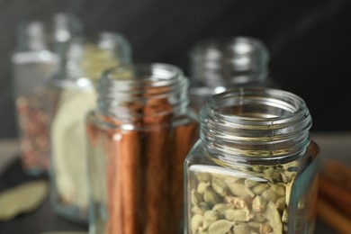 Different spices in glass jars on blurred background, closeup