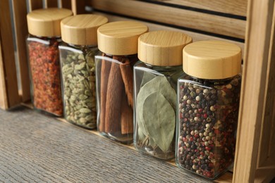 Different spices in glass jars on grey wooden table, closeup