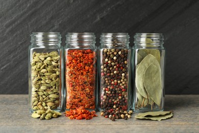 Different spices in glass jars on grey wooden table, closeup