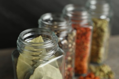 Photo of Different spices in glass jars on table, closeup