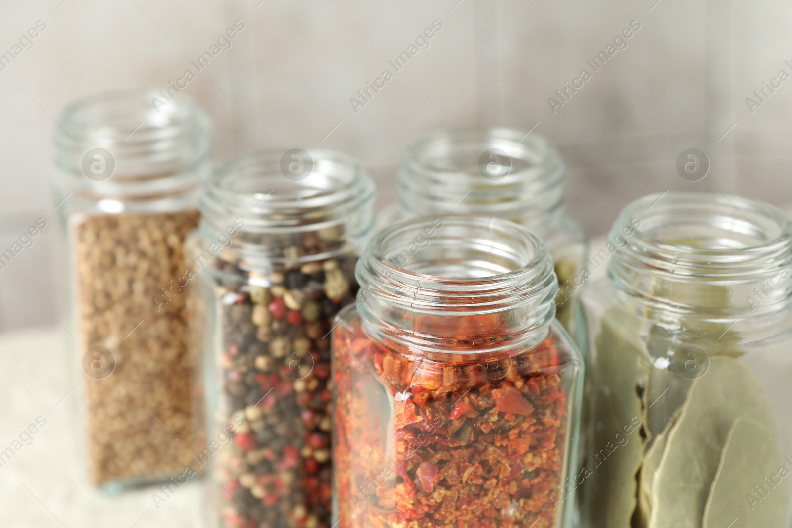 Photo of Different spices in glass jars on table, closeup