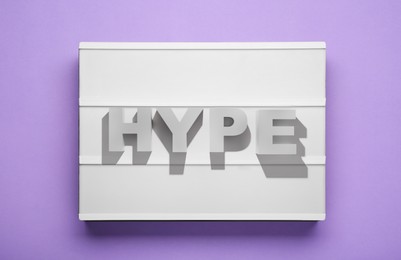 Lightbox with word Hype on violet background, top view