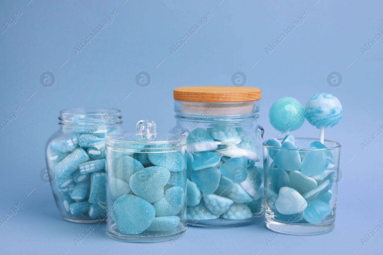 Image of Many bright candies in glass jars on light blue background