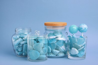 Image of Many bright candies in glass jars on light blue background