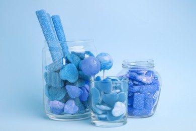 Image of Many bright candies in glass jars on light blue background