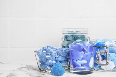 Image of Many blue color candies in glass jars on white marble table. Space for text