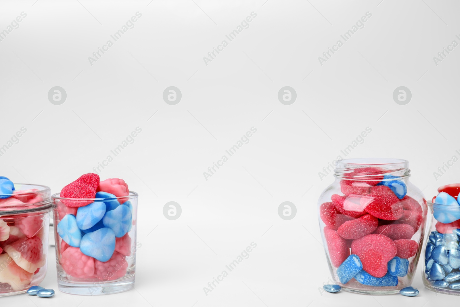 Image of Many bright candies in glass jars on light table. Space for text