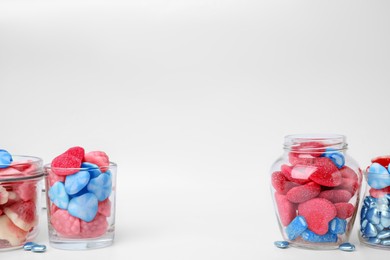 Many bright candies in glass jars on light table. Space for text