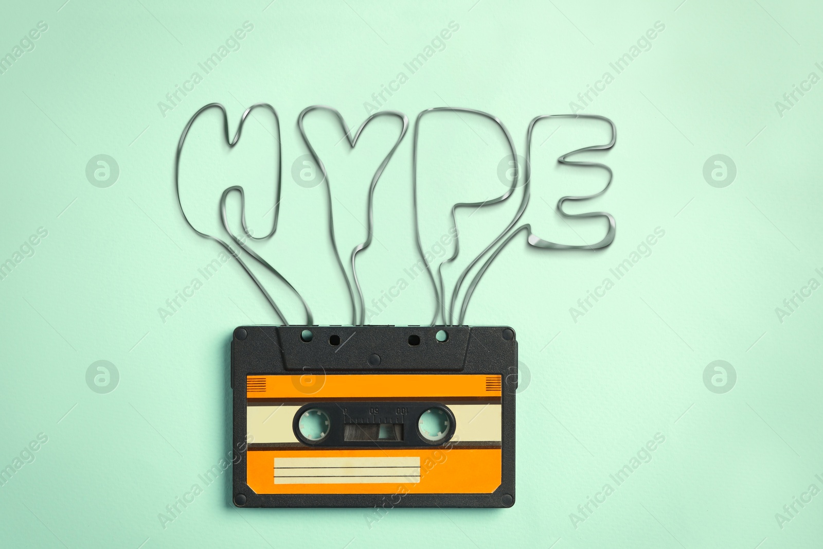 Illustration of Hype word made of audio cassette tape on light turquoise background, top view