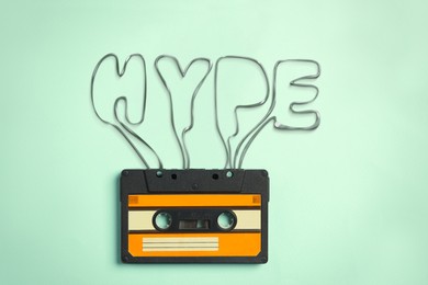 Hype word made of audio cassette tape on light turquoise background, top view