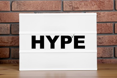 Hype word on sheet of paper against brick wall